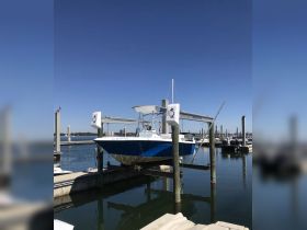 A sleek speedboat is docked at the marina, showcasing its vibrant blue hull against a clear sky — perfect for fishing or day trips on the water.