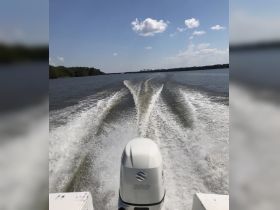 A view from the back of a boat showcasing the powerful wake as it cruises through calm waters, perfect for adventure seekers and boating enthusiasts.