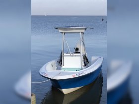 A sleek speedboat docked in calm waters, showcasing its vibrant blue hull and spacious design, perfect for fishing or leisure trips.