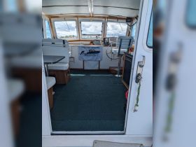 Interior view of a fishing charter boat's cabin, showcasing the helm and seating area, perfect for comfortable fishing trips.