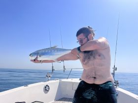 A proud angler displays his catch aboard a boat, showcasing the thrill of fishing on the open ocean.
