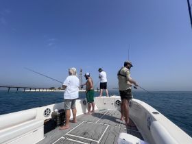 A group of friends enjoys a day of fishing on a boat, casting their lines into the clear blue ocean — a perfect outing for fishing enthusiasts.