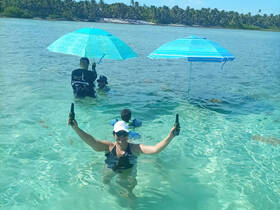 A joyful group enjoys a sunny day in shallow waters, celebrating with drinks and umbrellas — the perfect beach getaway.