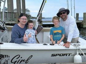 A joyful family poses on a fishing boat, giving thumbs up for a fun day on the water — perfect for creating lasting memories together.