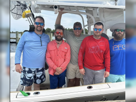 A group of friends poses together on a fishing boat, showcasing camaraderie and adventure on the water.