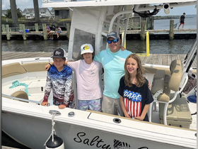 A joyful group of children and an adult pose aboard a boat, ready for a fun day on the water. Perfect for family fishing trips or summer adventures.