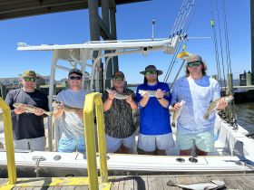 A group of friends proudly displays their catch after a successful fishing trip, showcasing the camaraderie and excitement of a day on the water.