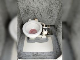 Interior view of a boat's bathroom featuring a marine toilet, showcasing the essential amenities for comfort on the water.