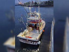 A fishing boat named 'FISHBUCKET' is docked, showcasing its fishing gear and spacious deck, perfect for a day out on the water.