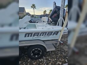 A close-up view of a custom MAMBA boat, showcasing its sleek design and features while docked, perfect for fishing or leisure activities.