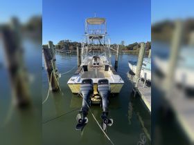 A clear view of a fishing boat docked at the marina, showcasing its twin engines and spacious layout, perfect for fishing enthusiasts.