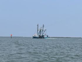 A fishing boat navigates through calm waters, showcasing its structure and design while underway.