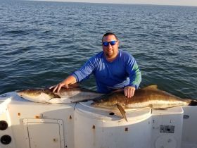 A proud angler displays his impressive catch aboard a boat, showcasing the thrill of fishing on the open water.