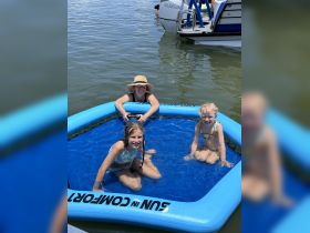 A joyful family enjoys a sunny day in an inflatable pool on the water, creating lasting memories of summer fun.