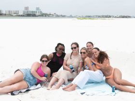 A fun group of friends relaxes on the beach, enjoying drinks and each other's company — perfect for summer celebrations and beach outings.