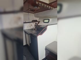Interior view of a boat's cabin featuring a compact kitchen area with a sink and storage, ideal for meal preparation while on the water.
