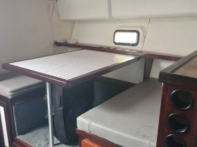 Interior view of a cozy boat cabin featuring a dining area with a table and seating, perfect for relaxing meals while on the water.