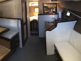 Interior view of a boat cabin showcasing seating and a compact kitchen area, perfect for comfortable cruising and relaxation on the water.