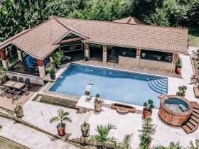 Aerial view of a pool area with a covered patio and surrounding greenery, ideal for relaxation and outdoor gatherings.