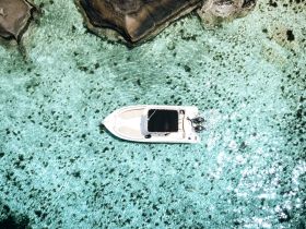 A stunning aerial view of a speedboat gliding through crystal-clear waters, showcasing the vibrant marine life below — perfect for exploring secluded beaches and hidden coves.
