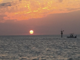 A stunning sunset over the ocean with a boat silhouetted against the vibrant sky, creating a picturesque scene perfect for evening cruises.