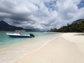 A speedboat rests on the sandy shore, surrounded by stunning turquoise waters and lush greenery, perfect for a day of adventure in paradise.