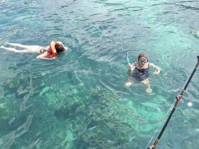 Two snorkelers enjoy a vibrant underwater experience, surrounded by colorful fish in crystal-clear waters — a perfect adventure for families and friends.