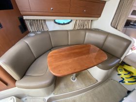Cozy seating area inside a boat, featuring a wooden table and comfortable cushions, perfect for dining or relaxing while on the water.