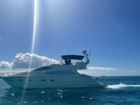 A stunning yacht glides through clear blue waters under a bright sky, showcasing its elegant design and perfect for luxury cruising.