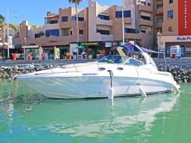 A sleek speedboat docked in a vibrant marina, surrounded by colorful shops and restaurants, perfect for a day on the water.