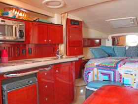 Interior view of a cozy boat cabin featuring a well-equipped kitchen area and comfortable sleeping space, perfect for relaxing during a day on the water.