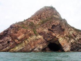 A stunning view of a rocky coastline featuring a prominent cave, perfect for exploring the natural beauty of the area while on a boat tour.