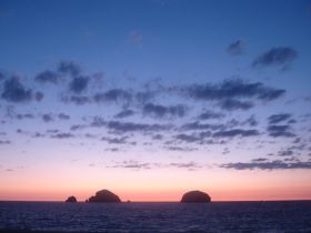 A stunning sunset view over the ocean, featuring silhouetted islands against a colorful sky — perfect for capturing the beauty of nature during a boating trip.