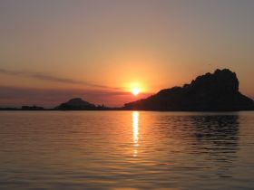 A breathtaking sunset over tranquil waters, with silhouetted islands creating a picturesque backdrop — ideal for romantic evenings or serene boat trips.