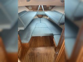 Interior view of a cozy boat cabin featuring comfortable seating and wooden flooring, perfect for relaxing during a sailing trip.