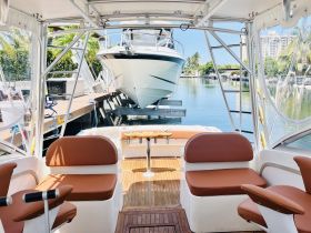 Interior view of a boat cabin featuring comfortable seating and a clear view of the docked vessel outside, perfect for relaxing before setting sail.