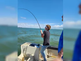 A young angler reels in a catch while fishing on a boat, showcasing the excitement of a day on the water.
