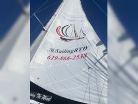 Close-up of a sailboat's sail featuring the boat name and contact information, ideal for sailing enthusiasts and charter services.