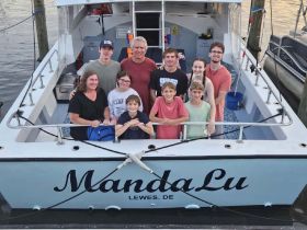 A cheerful group of family and friends poses aboard the MandaLu, capturing a memorable moment on their boating adventure.