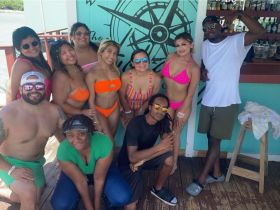 A vibrant group of friends poses for a fun photo at a beach bar, showcasing the joy of summer celebrations and memorable moments together.