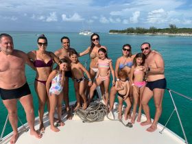 A joyful family poses on the deck of a boat, enjoying a sunny day in the turquoise waters — perfect for memorable gatherings and aquatic adventures.