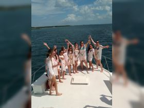 A lively group of friends celebrates on the deck of a boat, raising their drinks in a joyful toast — perfect for bachelorette parties or fun outings on the water.