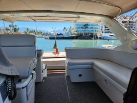 Interior view of a boat's cabin showcasing comfortable seating and a scenic waterfront backdrop, perfect for relaxing while enjoying the marine environment.