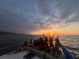 A lively group of friends celebrates at sunset aboard a yacht, capturing the perfect moment of joy and camaraderie on the water.
