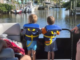 Two children in life jackets enjoy the view from the back of a boat, capturing the essence of family fun on the water.