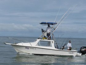 A fishing boat with crew members actively engaged in fishing on the open ocean, showcasing the excitement of a day out on the water.