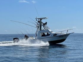 A fishing boat speeds through the water, showcasing an exciting day on the ocean with anglers ready for a catch.