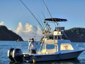 A fishing boat named 'Allin' is docked in calm waters, showcasing its fishing gear and scenic backdrop of hills — perfect for anglers looking for a day on the water.