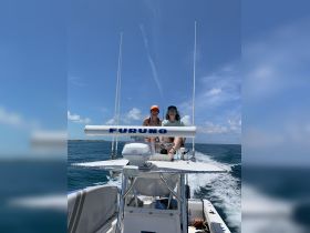 Two friends enjoy a sunny day on the water, capturing the thrill of boating and friendship aboard a sleek vessel.