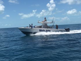 A fishing boat speeds through the clear blue waters, showcasing a group of anglers enjoying their day on the sea — perfect for fishing adventures and ocean exploration.